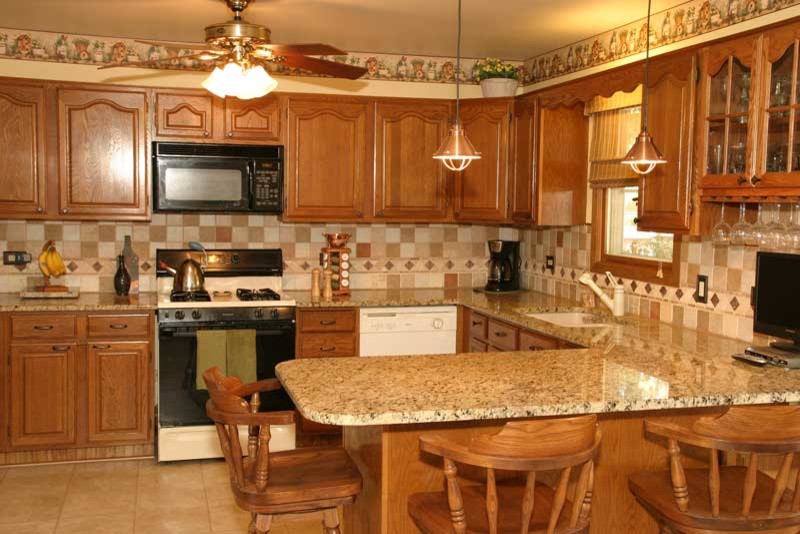 Inspiration for a transitional u-shaped medium tone wood floor kitchen pantry remodel in Chicago with raised-panel cabinets, medium tone wood cabinets and granite countertops