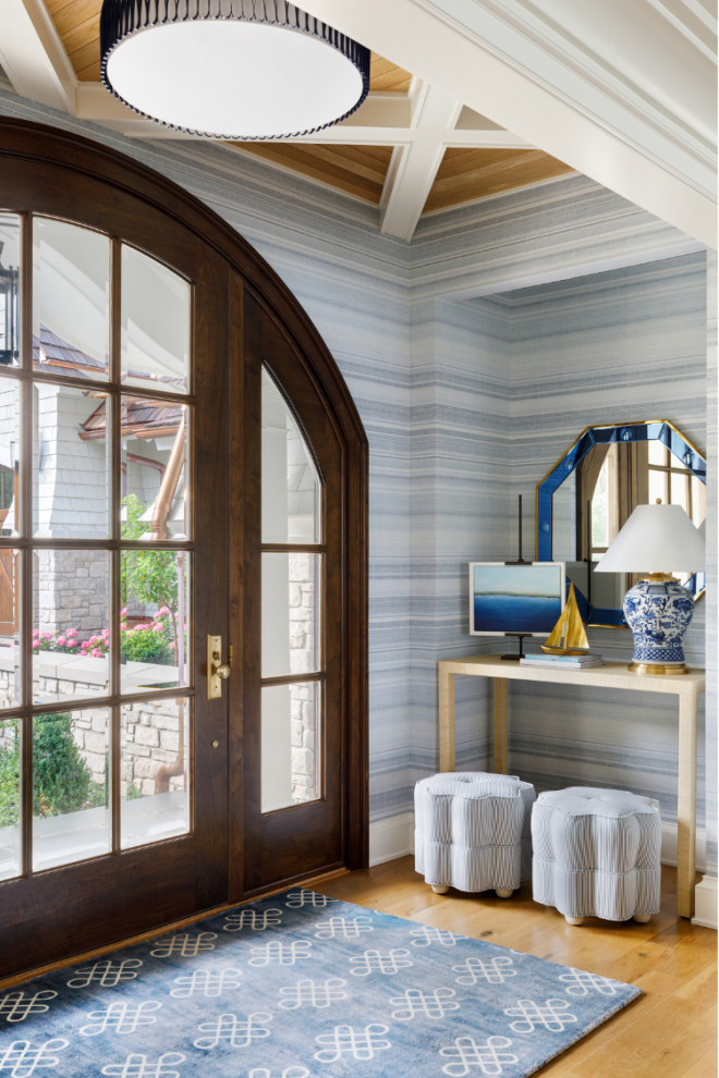 Cette photo montre une grande porte d'entrée bord de mer avec un mur bleu, parquet clair, une porte simple, une porte en bois foncé, un plafond à caissons et du papier peint.