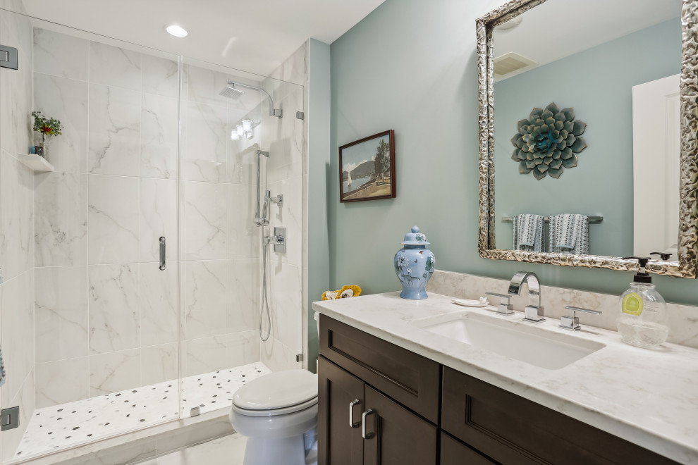 Inspiration for a small traditional 3/4 bathroom in DC Metro with recessed-panel cabinets, brown cabinets, an alcove shower, beige tile, ceramic tile, blue walls, ceramic floors, an undermount sink, engineered quartz benchtops, grey floor, a hinged shower door, beige benchtops, a single vanity and a built-in vanity.