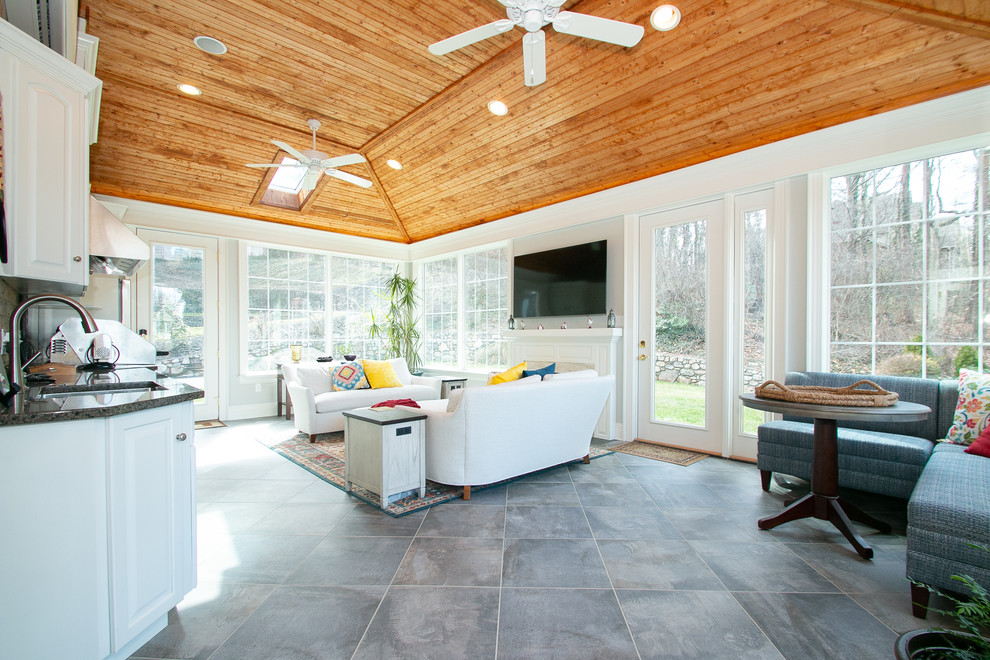This is an example of a large traditional sunroom in Other with porcelain floors, a standard fireplace, a stone fireplace surround, a skylight and grey floor.