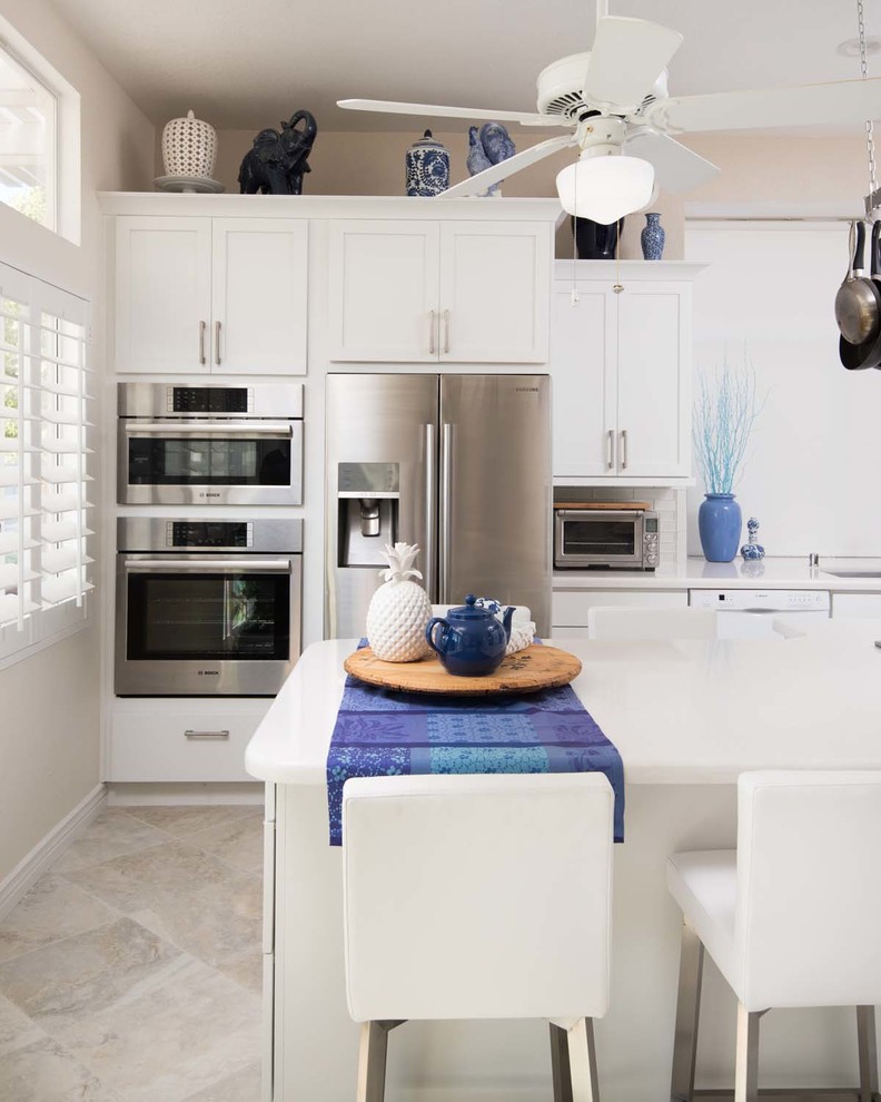 Inspiration for a mid-sized contemporary l-shaped kitchen pantry in San Diego with an undermount sink, shaker cabinets, white cabinets, quartz benchtops, white splashback, subway tile splashback, stainless steel appliances, porcelain floors and with island.