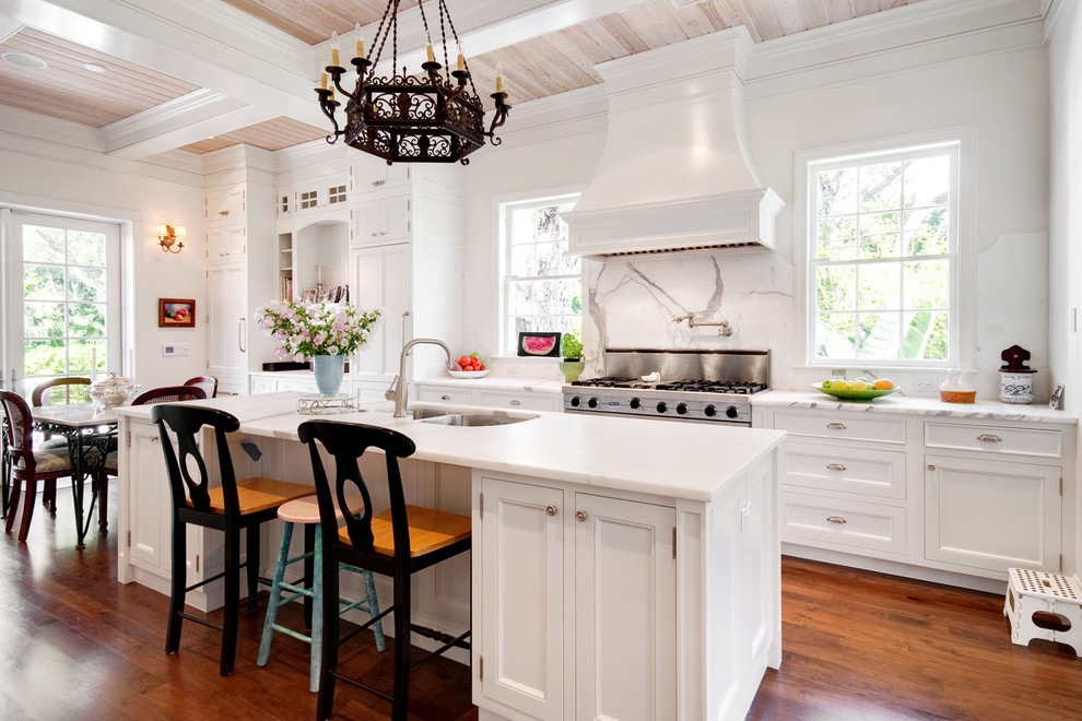 Inspiration for a traditional eat-in kitchen in Denver with a double-bowl sink, recessed-panel cabinets, white cabinets, white splashback, stainless steel appliances, medium hardwood floors and with island.
