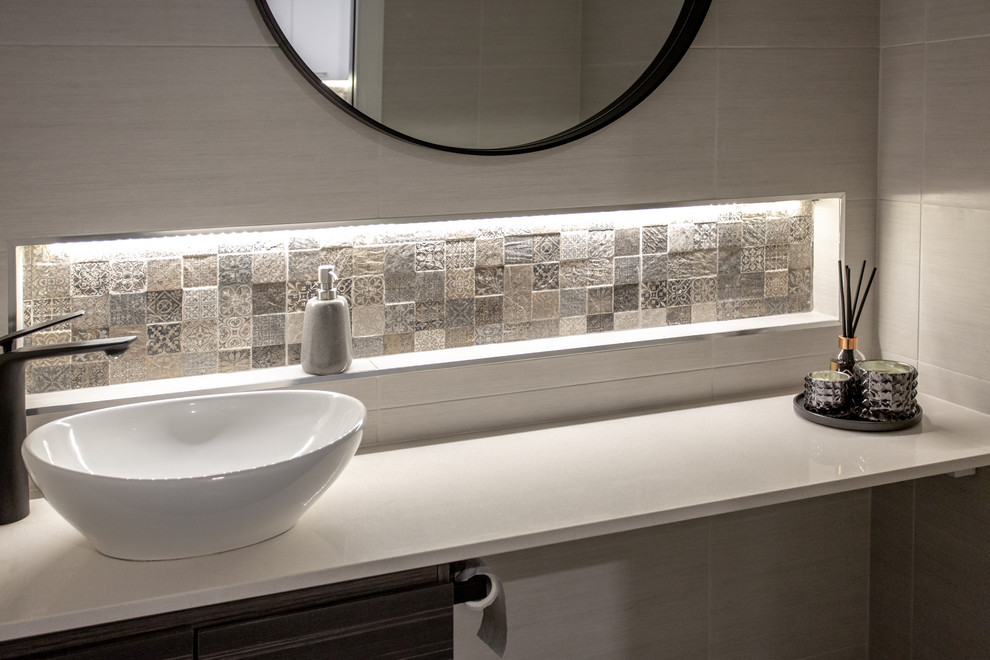 This is an example of a mid-sized contemporary powder room in Sydney with flat-panel cabinets, brown cabinets, white tile, ceramic tile, engineered quartz benchtops and white benchtops.