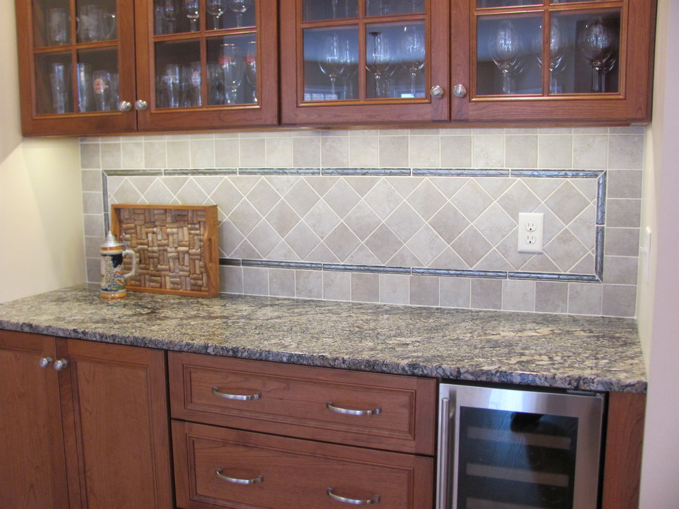 Inspiration for a large timeless single-wall home design remodel with raised-panel cabinets, medium tone wood cabinets, granite countertops, gray backsplash, porcelain backsplash, stainless steel appliances and an island