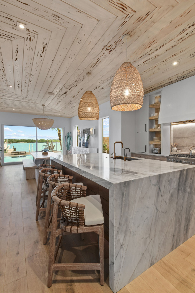 Mid-sized beach style l-shaped open plan kitchen in Other with distressed cabinets, quartzite benchtops, panelled appliances and with island.