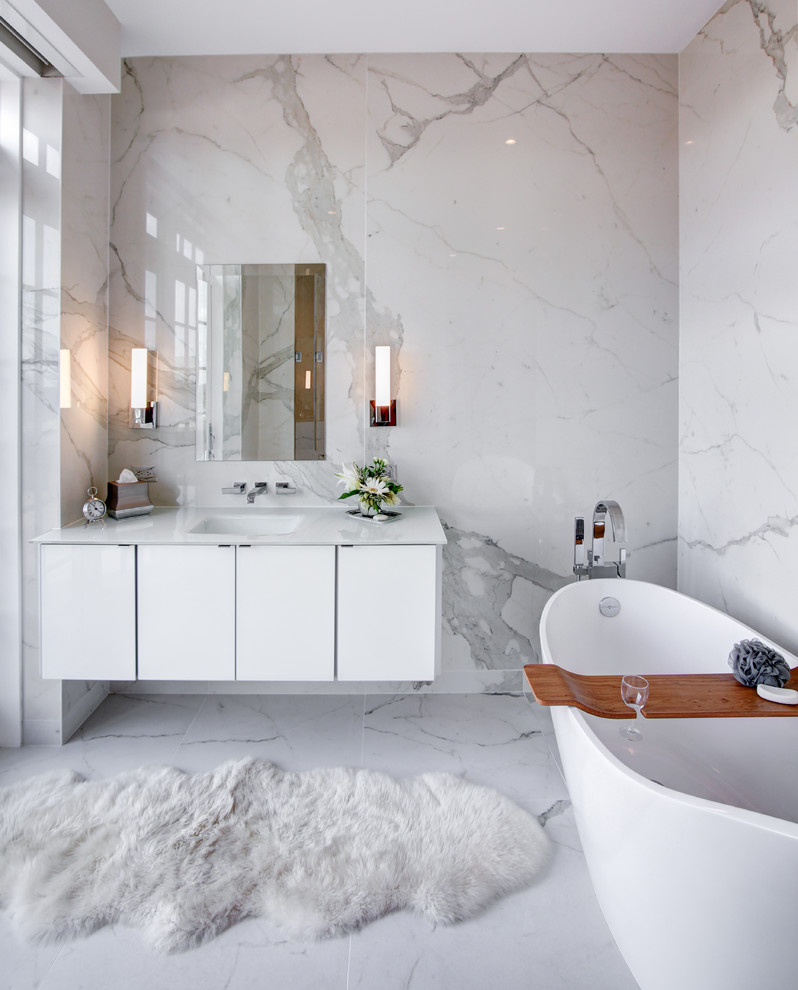 Inspiration for a contemporary master bathroom in Indianapolis with flat-panel cabinets, white cabinets, a freestanding tub, white tile, marble, white walls, marble floors, an integrated sink and white floor.