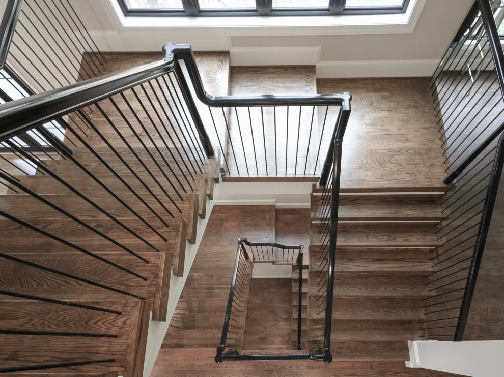 На фото: огромная п-образная деревянная лестница в стиле фьюжн с деревянными ступенями и перилами из смешанных материалов с