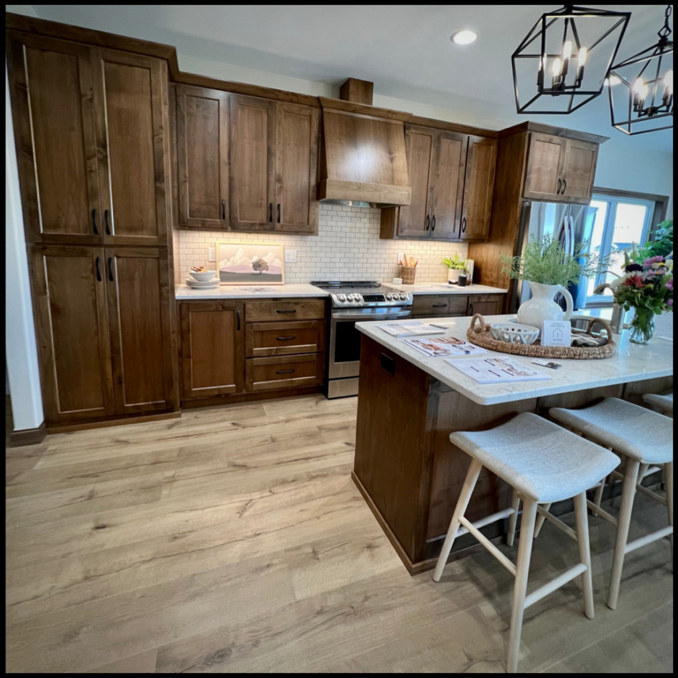 Example of a mountain style kitchen design with dark wood cabinets, white backsplash, stainless steel appliances, an island and white countertops