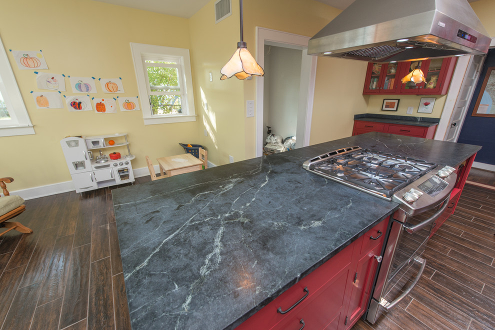 Eat-in kitchen - mid-sized contemporary galley dark wood floor and brown floor eat-in kitchen idea with a double-bowl sink, raised-panel cabinets, red cabinets, soapstone countertops, stainless steel appliances and an island