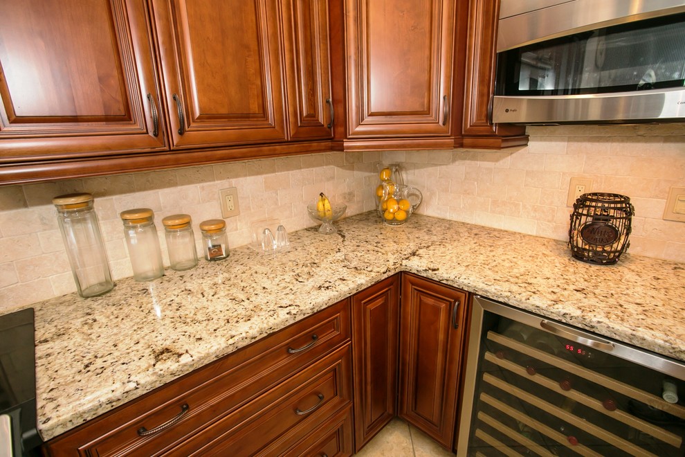 Example of a mid-sized transitional u-shaped porcelain tile eat-in kitchen design in Miami with an undermount sink, raised-panel cabinets, brown cabinets, granite countertops, beige backsplash, stone tile backsplash, stainless steel appliances, beige walls and a peninsula