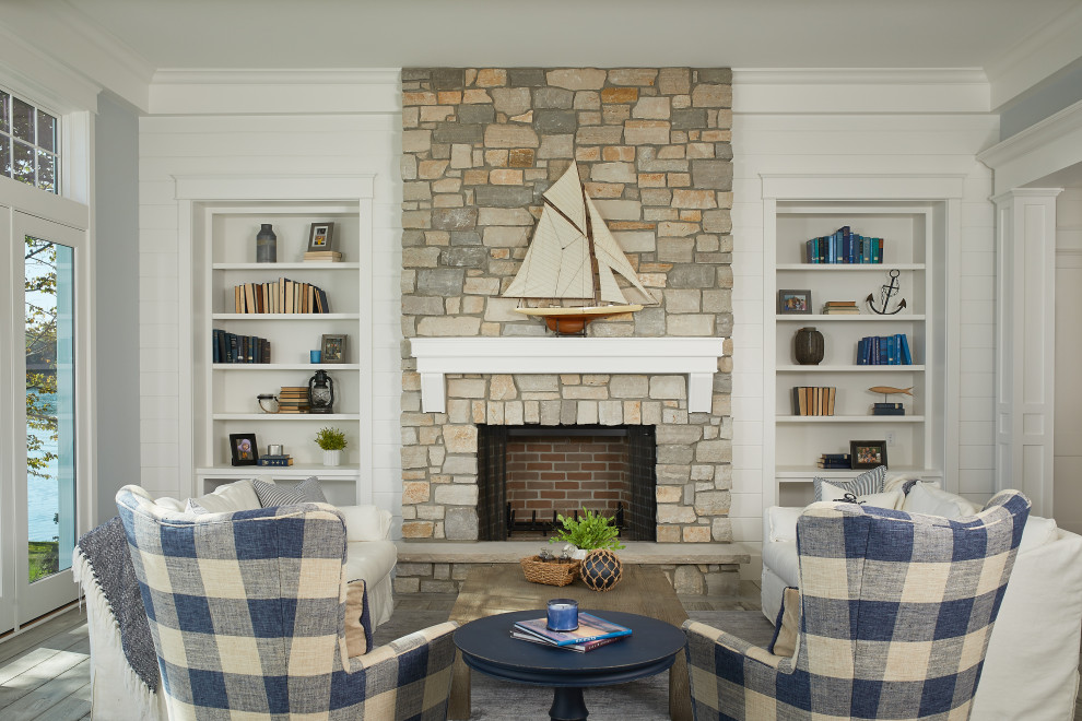 Photo of a beach style open concept living room in Grand Rapids with a standard fireplace, a stone fireplace surround, no tv, planked wall panelling, white walls, medium hardwood floors and brown floor.