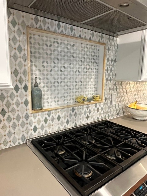 Large transitional u-shaped eat-in kitchen photo with raised-panel cabinets, white cabinets, quartz countertops, green backsplash, mosaic tile backsplash, stainless steel appliances, an island and green countertops