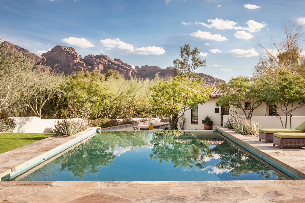 This is an example of a large mediterranean rectangular lap pool in Phoenix with natural stone pavers.