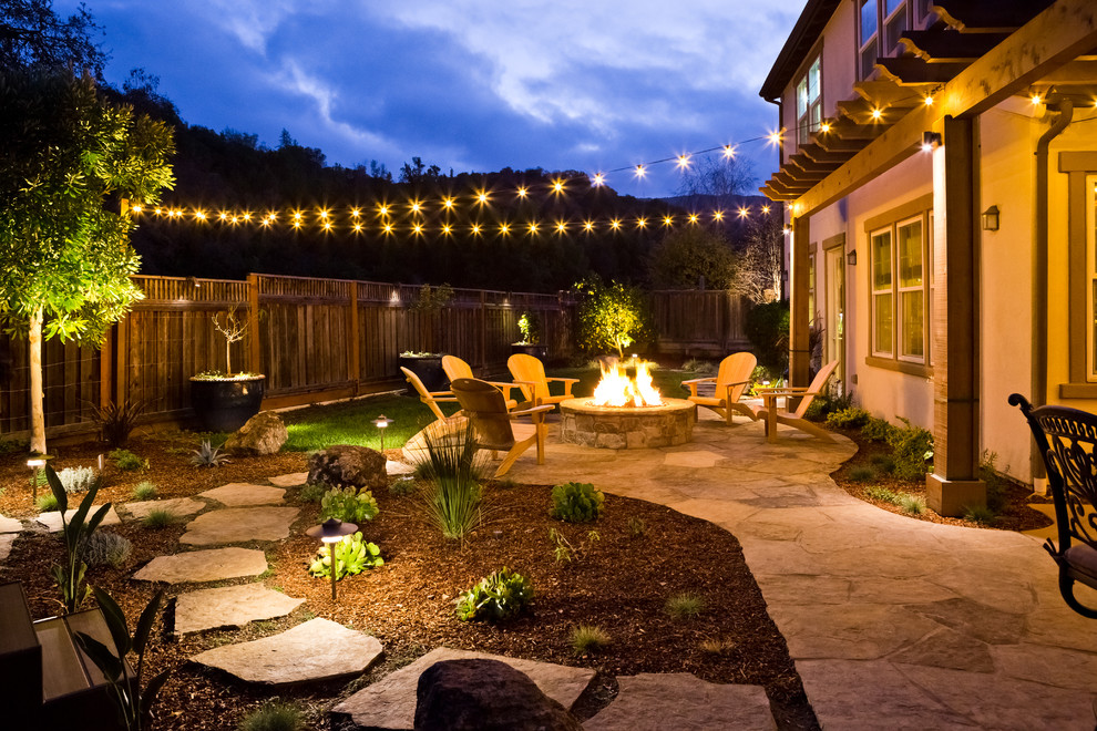 This is an example of a mid-sized country backyard patio in San Francisco with a fire feature and natural stone pavers.