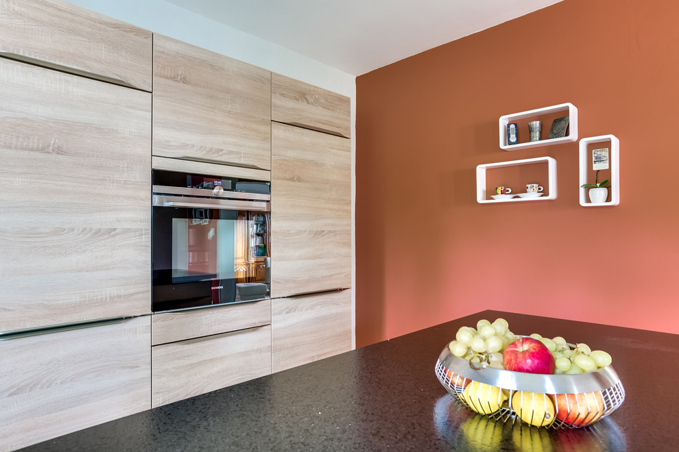 Photo of a contemporary eat-in kitchen in Nancy with flat-panel cabinets, light wood cabinets and with island.