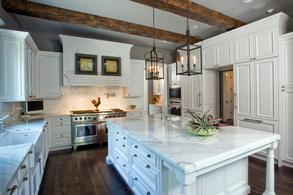 Photo of an expansive traditional u-shaped open plan kitchen in Chicago with panelled appliances, a farmhouse sink, raised-panel cabinets, white cabinets, marble benchtops, white splashback, ceramic splashback, dark hardwood floors and with island.