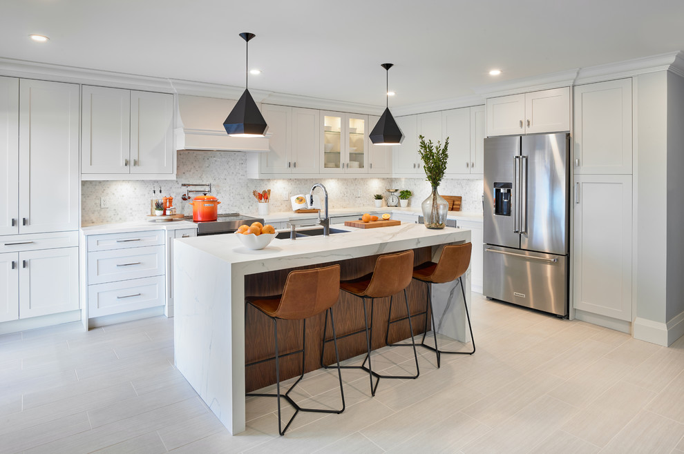 Example of a transitional l-shaped beige floor kitchen design in Toronto with a double-bowl sink, shaker cabinets, white cabinets, white backsplash, mosaic tile backsplash, stainless steel appliances and an island