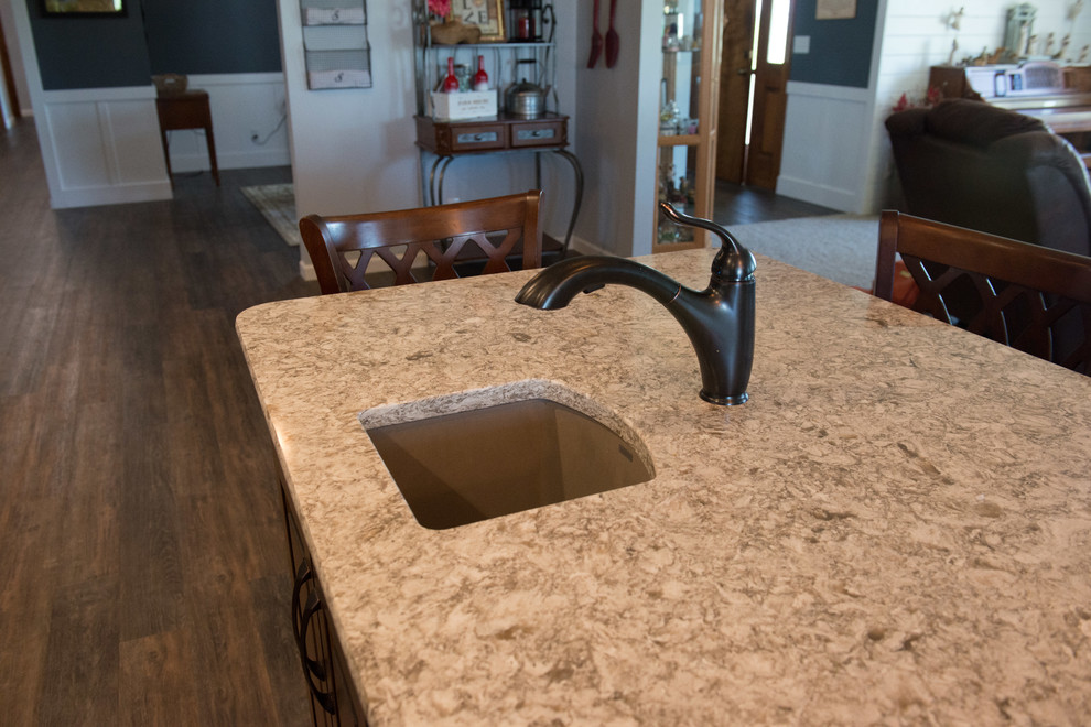 Huge transitional l-shaped medium tone wood floor home design photo with a farmhouse sink, raised-panel cabinets, medium tone wood cabinets, quartz countertops, gray backsplash, subway tile backsplash, stainless steel appliances, an island and multicolored countertops