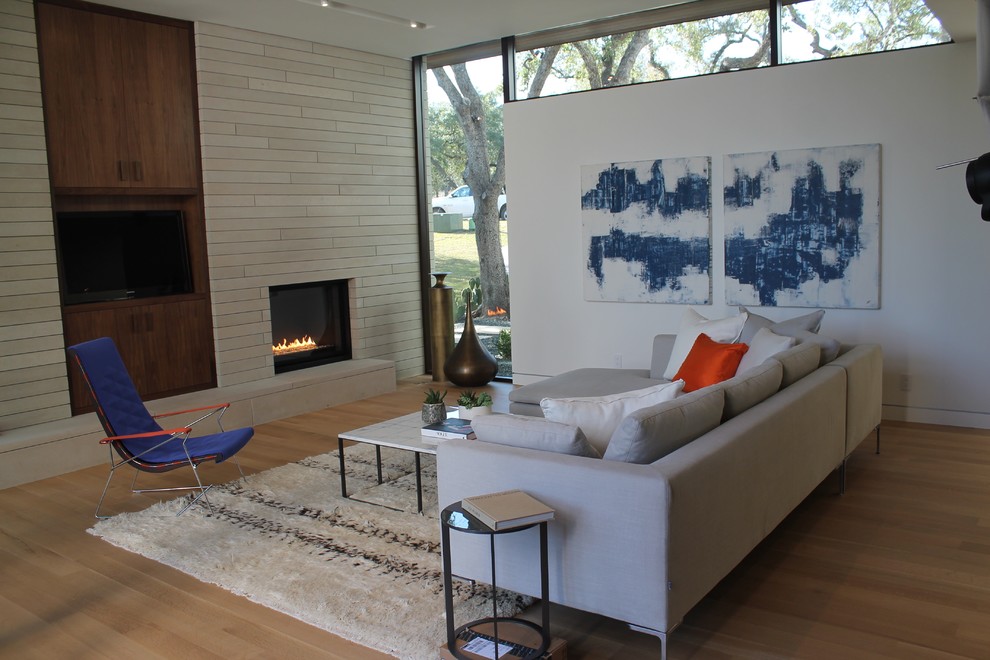 Design ideas for a mid-sized midcentury formal open concept living room in Austin with white walls, medium hardwood floors, a standard fireplace, a tile fireplace surround and a built-in media wall.