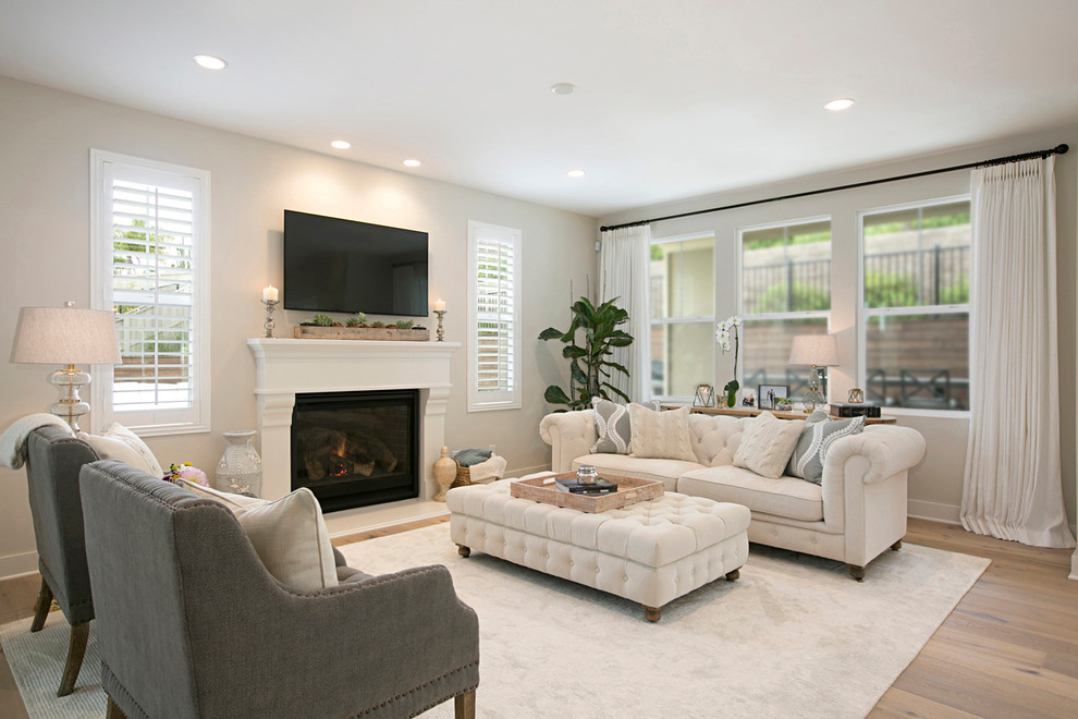 Inspiration for a mid-sized transitional open concept living room in San Diego with beige walls, medium hardwood floors, a standard fireplace, a stone fireplace surround, a wall-mounted tv and beige floor.