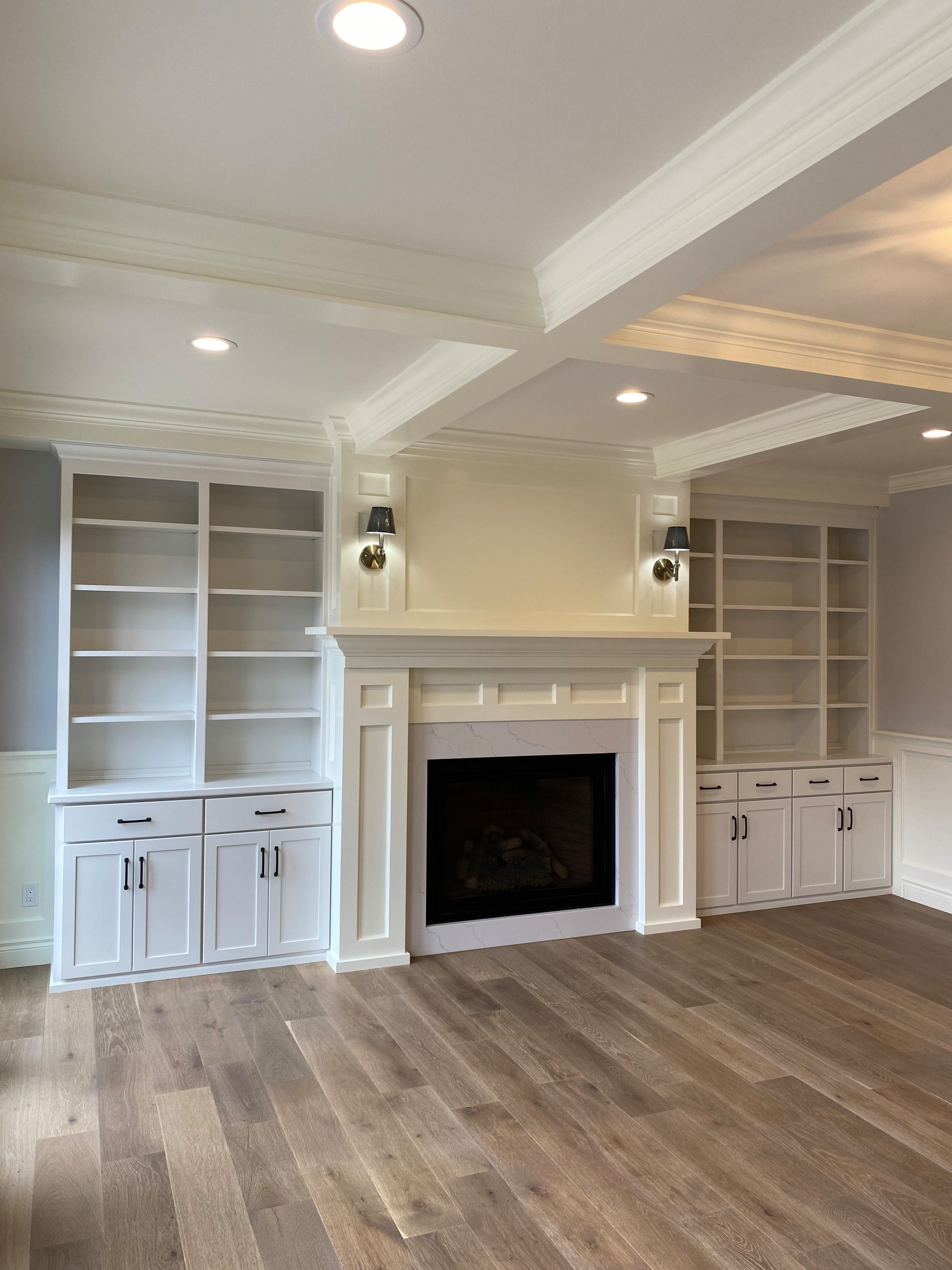 Gas log fireplace with painted custom built-ins and coffered ceiling