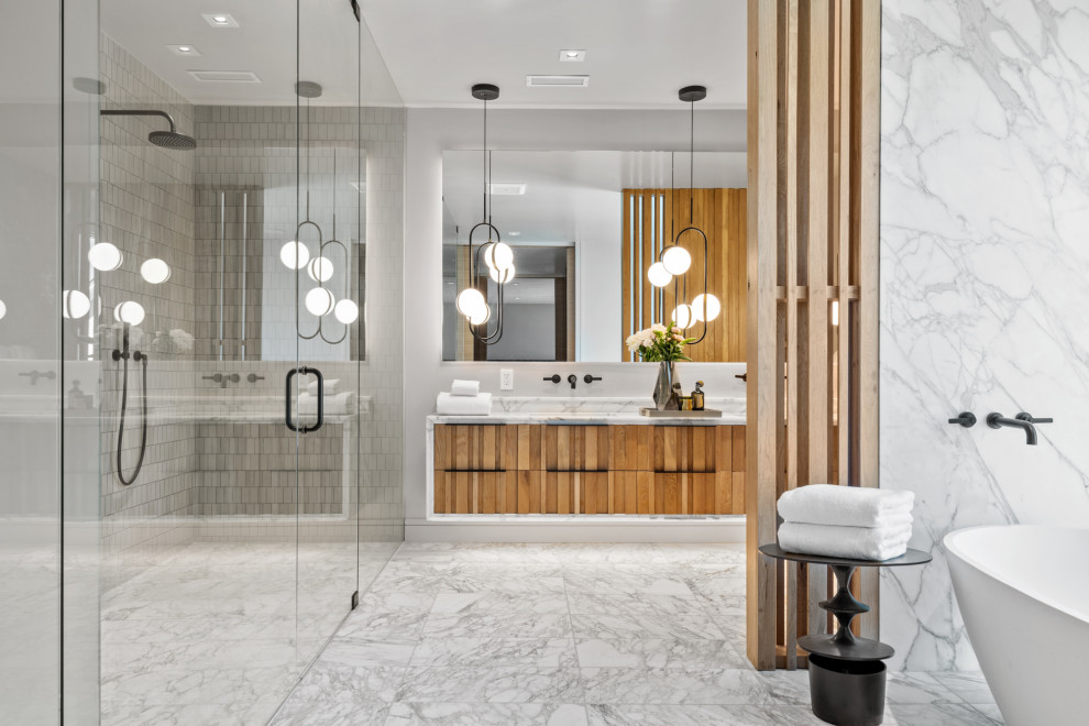 This is an example of a large contemporary master bathroom in San Francisco with louvered cabinets, medium wood cabinets, a freestanding tub, a curbless shower, a wall-mount toilet, beige tile, ceramic tile, yellow walls, marble floors, a drop-in sink, marble benchtops, yellow floor, a hinged shower door, yellow benchtops, an enclosed toilet, a double vanity and a floating vanity.