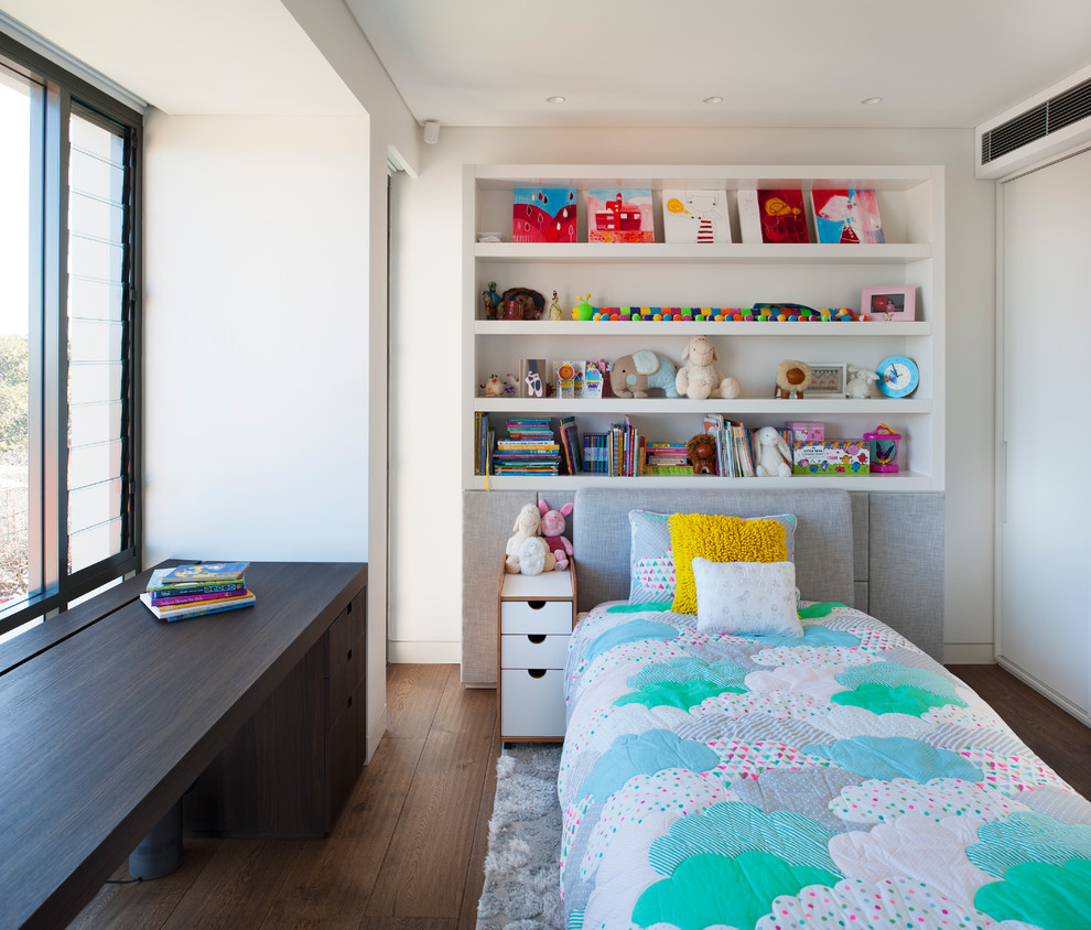 Photo of a contemporary gender-neutral kids' room for kids 4-10 years old in Sydney with white walls and medium hardwood floors.