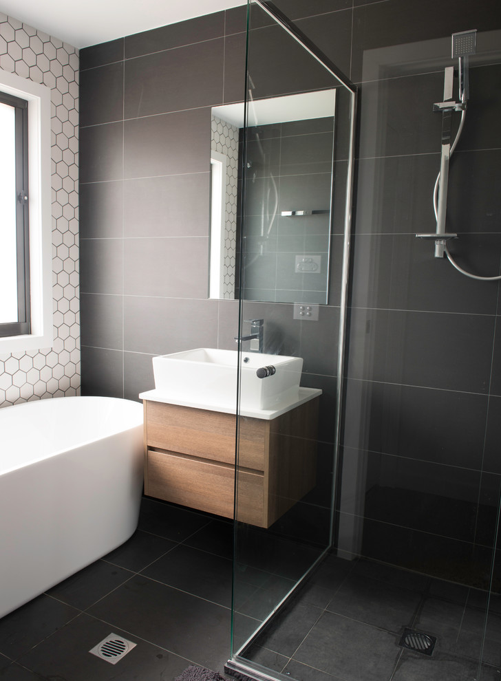 Photo of a mid-sized modern master bathroom in Canberra - Queanbeyan with a vessel sink, flat-panel cabinets, medium wood cabinets, a freestanding tub, an alcove shower, gray tile, ceramic tile, grey walls and ceramic floors.