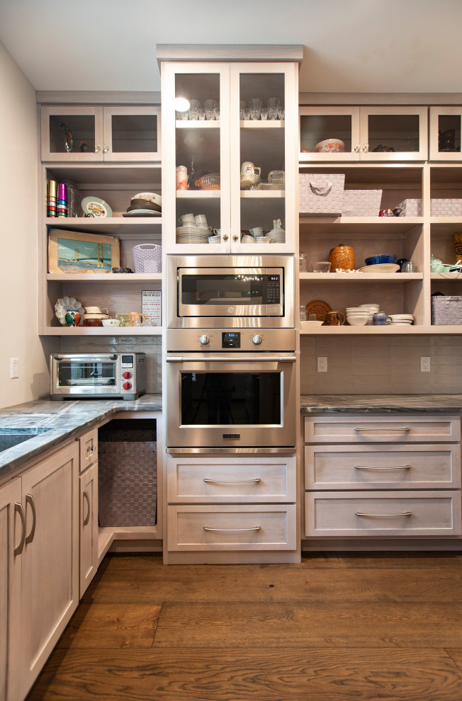 Example of a large mountain style l-shaped medium tone wood floor kitchen pantry design with an undermount sink, shaker cabinets, light wood cabinets, quartzite countertops, gray backsplash, ceramic backsplash and stainless steel appliances