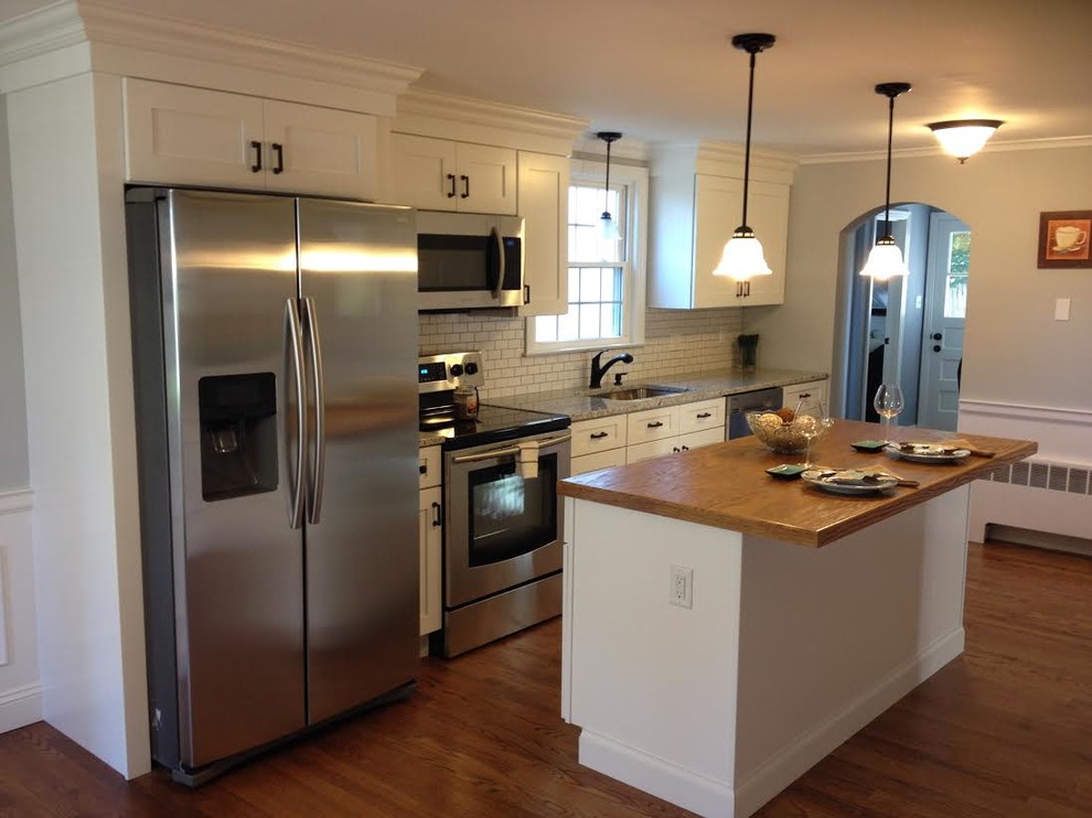 Mid-sized transitional single-wall medium tone wood floor open concept kitchen photo in Bridgeport with an undermount sink, shaker cabinets, white cabinets, granite countertops, white backsplash, subway tile backsplash, stainless steel appliances and an island