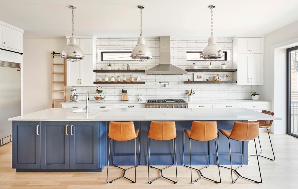 Inspiration for a mid-sized transitional l-shaped kitchen in Chicago with a farmhouse sink, shaker cabinets, quartzite benchtops, white splashback, ceramic splashback, stainless steel appliances, light hardwood floors, with island, white benchtop, white cabinets and beige floor.