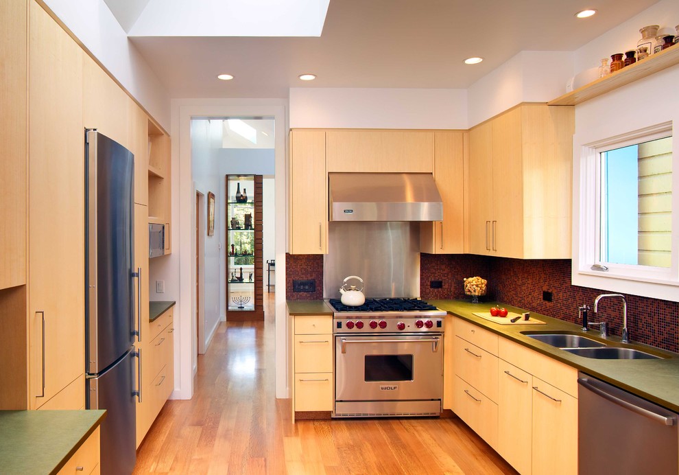 This is an example of a large contemporary eat-in kitchen in San Francisco with stainless steel appliances, an undermount sink, flat-panel cabinets, light wood cabinets, red splashback, medium hardwood floors and no island.