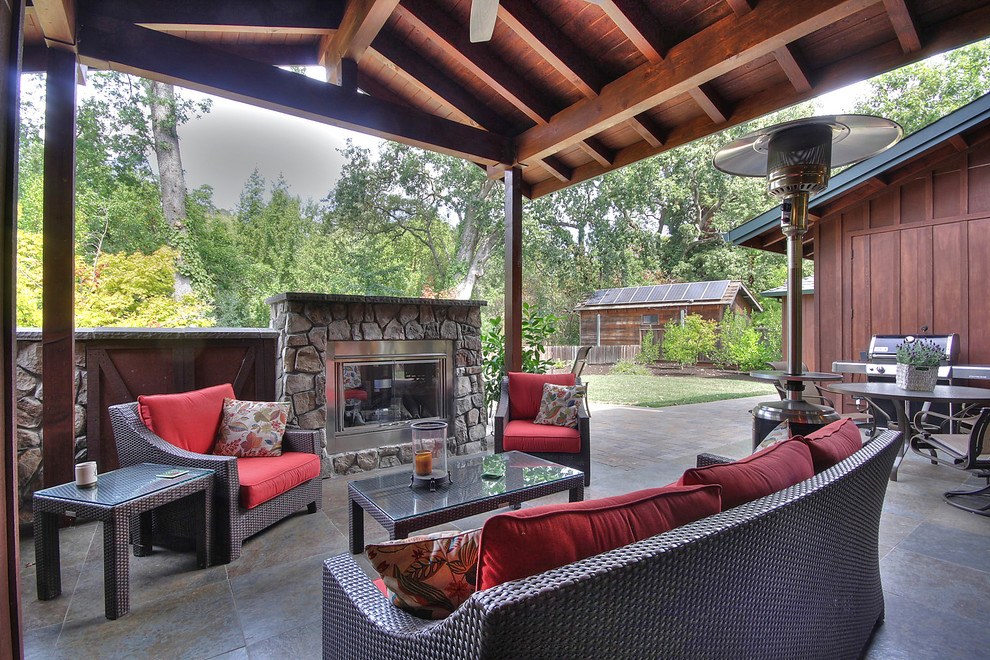 This is an example of a mid-sized arts and crafts backyard patio in San Francisco with a fire feature, tile and a roof extension.
