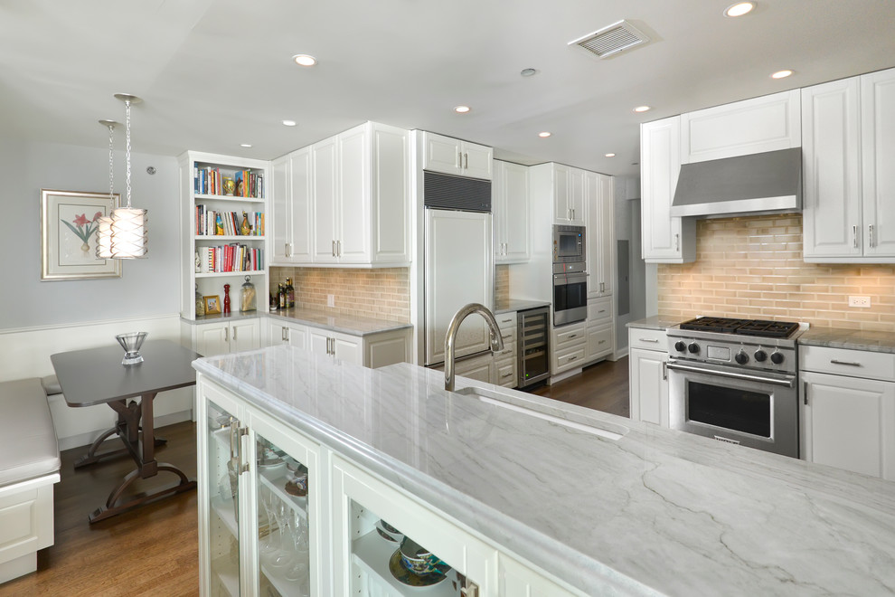 Design ideas for a mid-sized transitional l-shaped separate kitchen in Chicago with an undermount sink, raised-panel cabinets, white cabinets, granite benchtops, brown splashback, ceramic splashback, white appliances, medium hardwood floors and a peninsula.