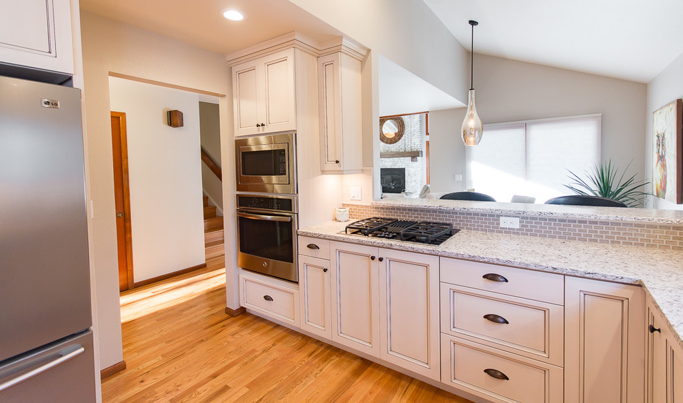 Inspiration for a transitional light wood floor and brown floor eat-in kitchen remodel with an undermount sink, shaker cabinets, white cabinets, quartz countertops, white backsplash, ceramic backsplash and stainless steel appliances