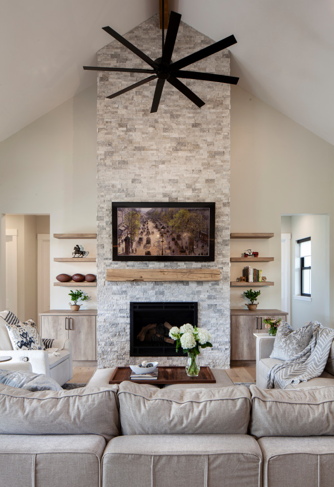 Large farmhouse open concept light wood floor, brown floor and vaulted ceiling living room photo in Denver with gray walls, a standard fireplace, a stacked stone fireplace and a wall-mounted tv