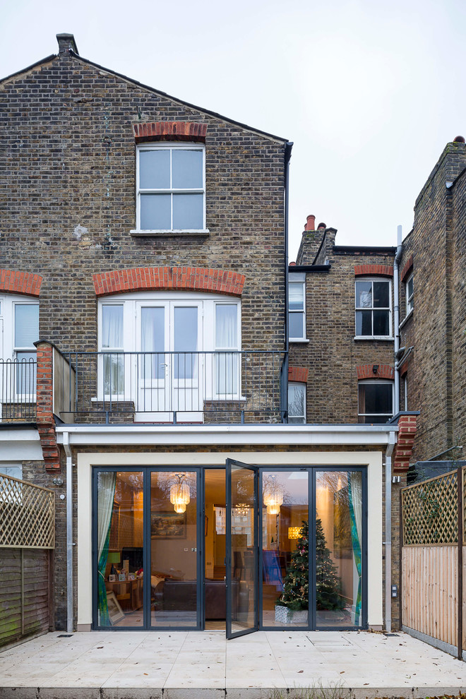 Design ideas for a mid-sized contemporary three-storey brick exterior in London with a flat roof.