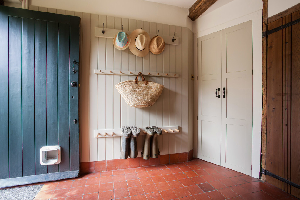Design ideas for a mid-sized country mudroom in Kent with beige walls, terra-cotta floors, orange floor, a pivot front door and a blue front door.
