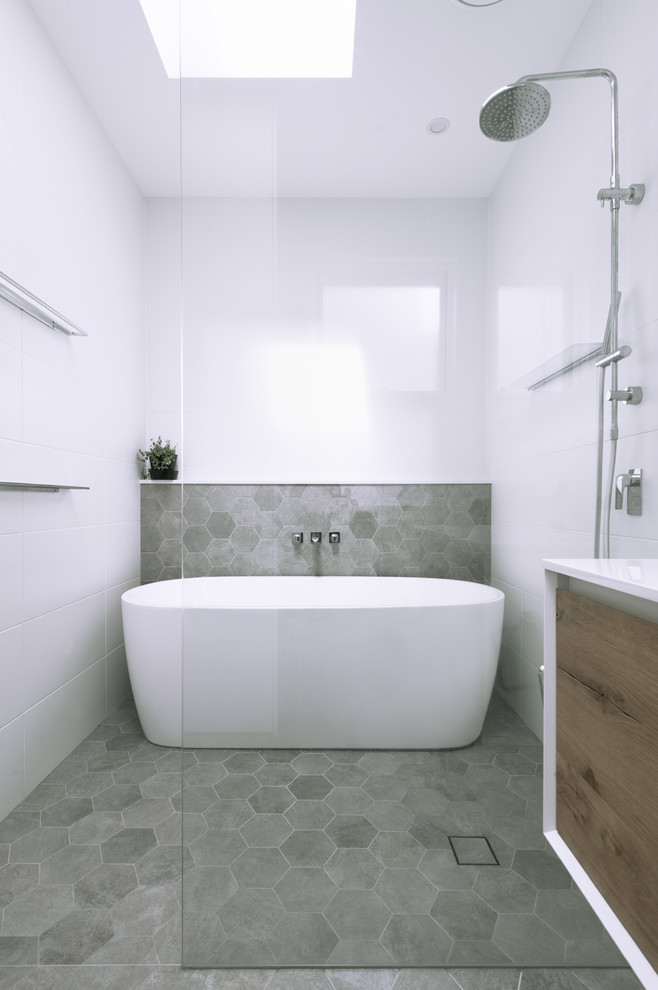 Inspiration for a mid-sized contemporary master bathroom in Sydney with flat-panel cabinets, light wood cabinets, a freestanding tub, an open shower, a one-piece toilet, white tile, subway tile, white walls, porcelain floors, a wall-mount sink, engineered quartz benchtops, grey floor, an open shower and white benchtops.