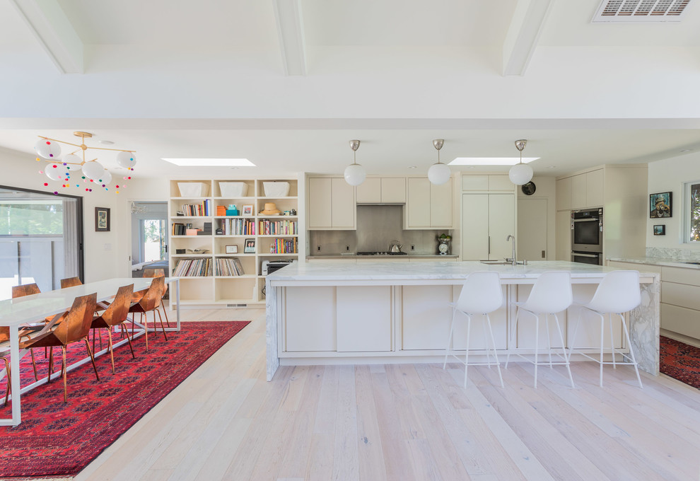 Design ideas for a midcentury open plan kitchen in San Francisco with an undermount sink, flat-panel cabinets, marble benchtops, panelled appliances, light hardwood floors, with island, white benchtop, beige cabinets, metallic splashback and beige floor.