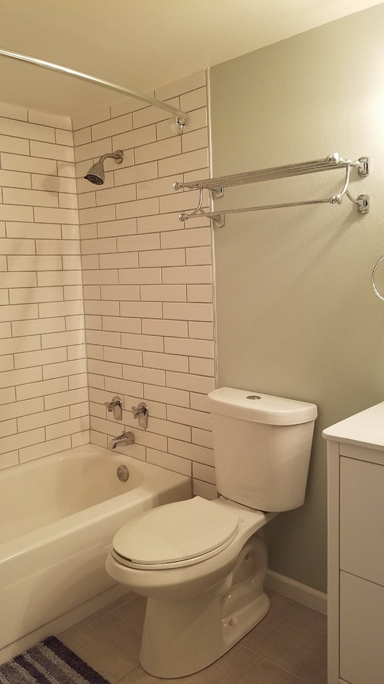 Example of a mid-sized transitional 3/4 white tile and subway tile porcelain tile and beige floor alcove bathtub design with flat-panel cabinets, white cabinets, a two-piece toilet, beige walls, an integrated sink, solid surface countertops and white countertops