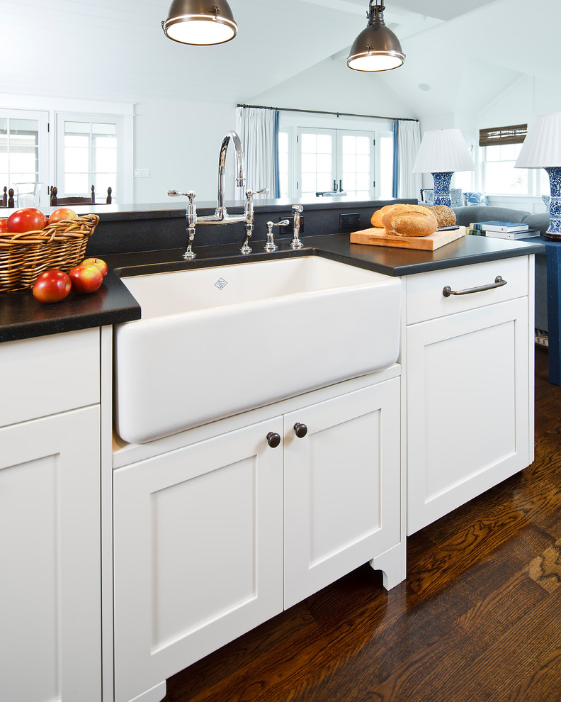 Photo of a beach style l-shaped eat-in kitchen in Other with a farmhouse sink, white cabinets, granite benchtops, white splashback, subway tile splashback, stainless steel appliances and recessed-panel cabinets.
