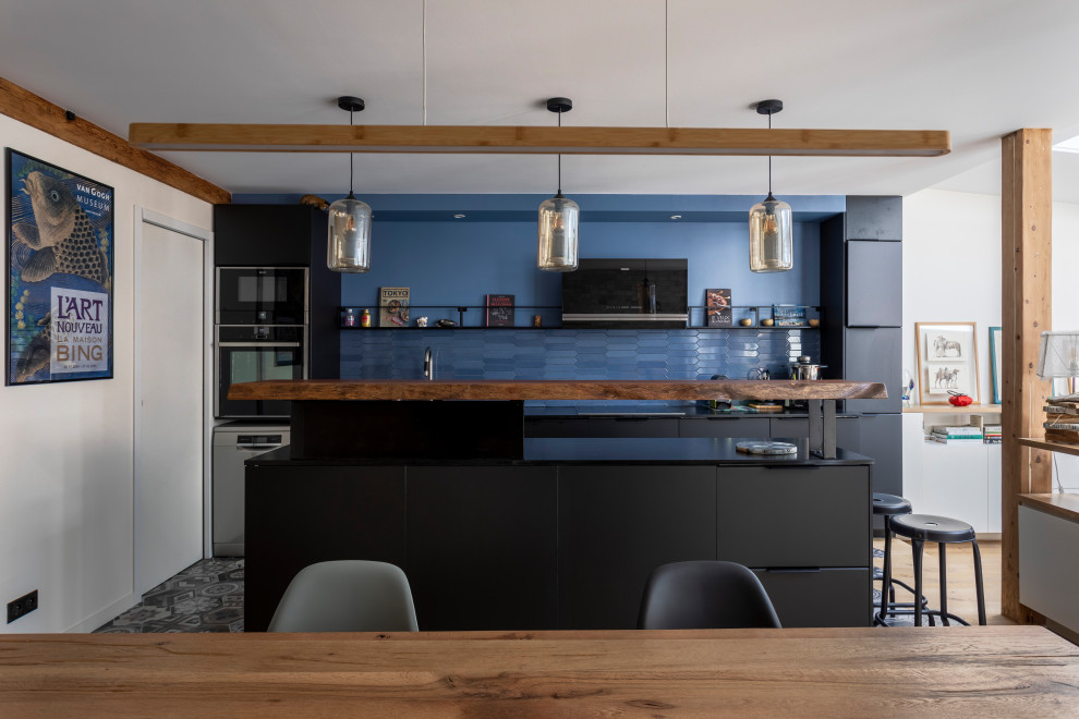 Photo of a large galley eat-in kitchen in Paris with an undermount sink, flat-panel cabinets, black cabinets, granite benchtops, blue splashback, porcelain splashback, panelled appliances, ceramic floors, with island, grey floor and black benchtop.