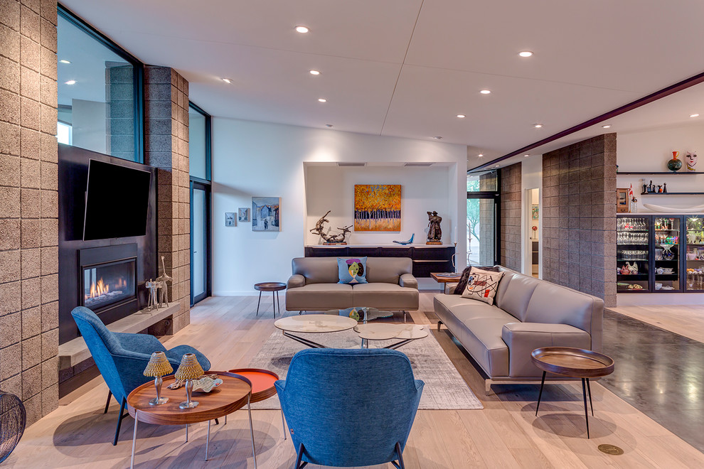 This is an example of a midcentury open concept family room in Phoenix with light hardwood floors, a metal fireplace surround, a wall-mounted tv, white walls, a ribbon fireplace and beige floor.
