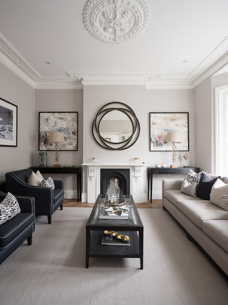 Photo of a transitional formal living room in London with grey walls, medium hardwood floors, a standard fireplace and no tv.