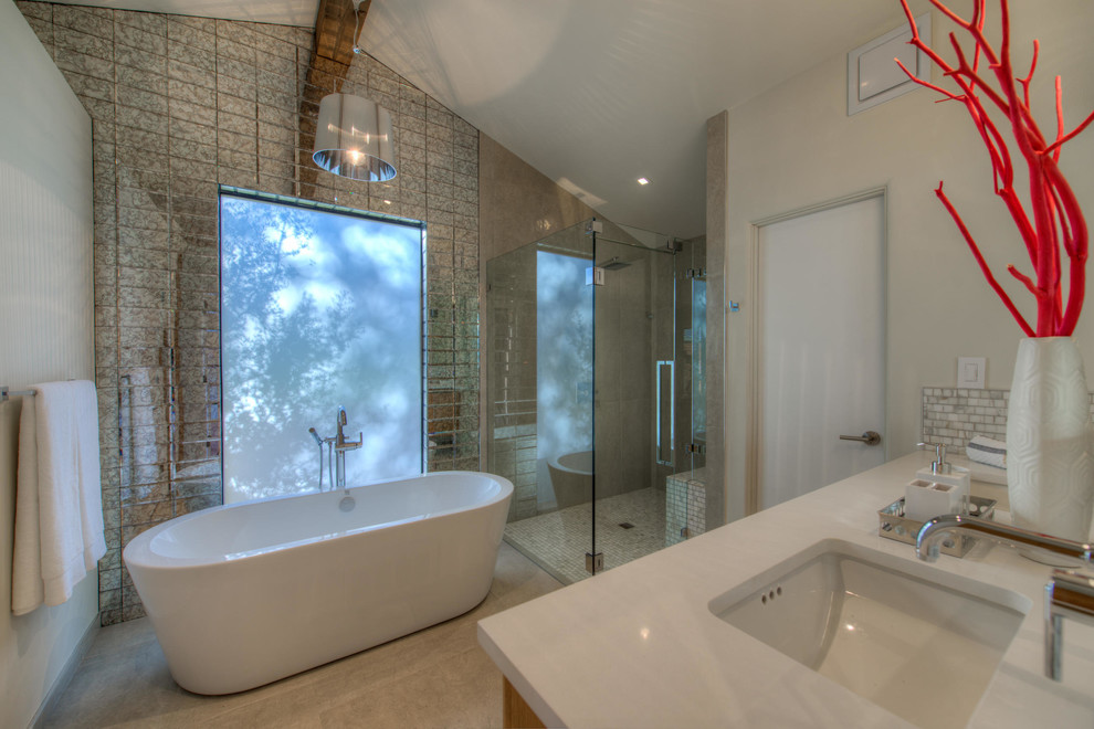 Inspiration for a contemporary master bathroom in Austin with flat-panel cabinets, medium wood cabinets, a freestanding tub, a corner shower, a one-piece toilet, gray tile, mirror tile, white walls, ceramic floors, an undermount sink and engineered quartz benchtops.