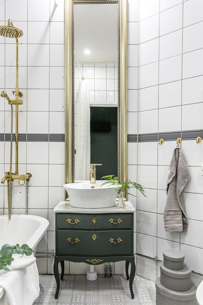 Design ideas for a mid-sized traditional bathroom in Malmo with green cabinets, a shower/bathtub combo, cement tiles, marble benchtops, multi-coloured floor, gray tile, white tile, a vessel sink and flat-panel cabinets.