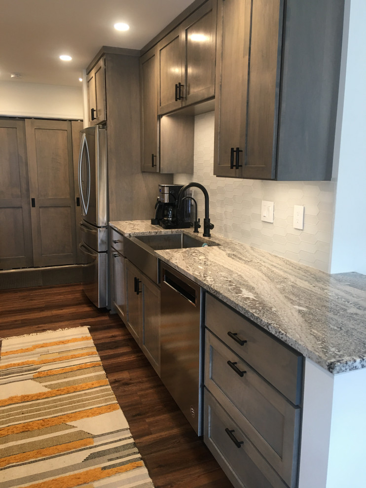 Design ideas for a mid-sized contemporary galley eat-in kitchen in Minneapolis with a farmhouse sink, shaker cabinets, grey cabinets, quartzite benchtops, white splashback, glass tile splashback, stainless steel appliances, vinyl floors, brown floor and grey benchtop.
