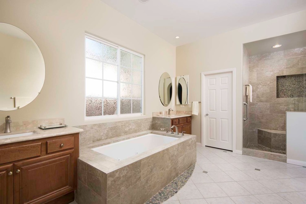 Large transitional master bathroom in San Diego with an undermount sink, raised-panel cabinets, medium wood cabinets, engineered quartz benchtops, a drop-in tub, an open shower, a one-piece toilet, beige tile, porcelain tile, beige walls and porcelain floors.