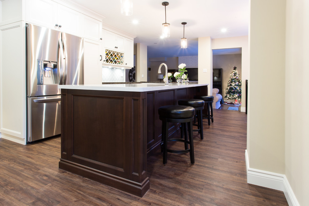 Eat-in kitchen - large transitional l-shaped dark wood floor eat-in kitchen idea in Orange County with a double-bowl sink, recessed-panel cabinets, white cabinets, granite countertops, gray backsplash, glass tile backsplash, stainless steel appliances and an island